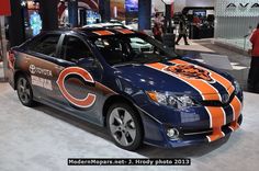 an orange and blue car with the chicago bears on it's hood is parked in a showroom