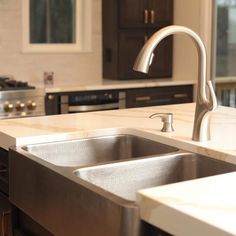 a stainless steel kitchen sink and faucet with marble counter tops in a home