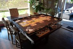 a board game sitting on top of a wooden table next to two chairs and a potted plant