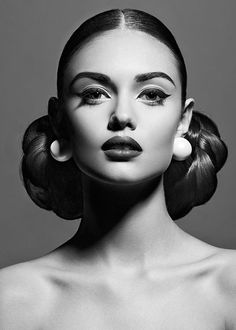 a black and white photo of a woman's face with her hair in buns