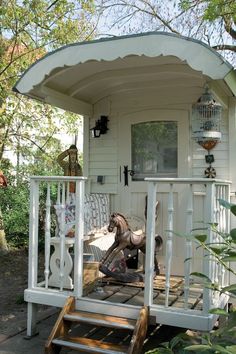 a small white house with a porch on the front and side steps leading up to it