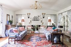 a living room with couches, chairs and rugs in front of two windows