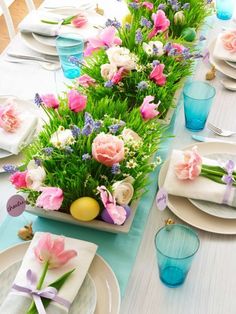 the table is set with plates and flowers in vases, napkins and place settings