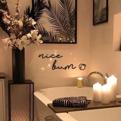 a white bath tub sitting next to a tall vase with flowers and candles on it