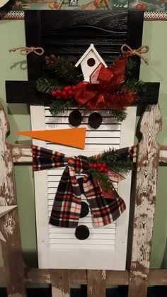 a snowman made out of an old shutter with red and black plaid scarfs