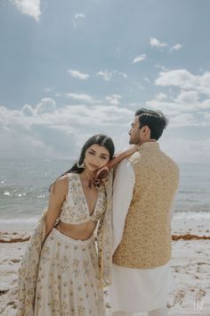 a man and woman standing next to each other on the beach