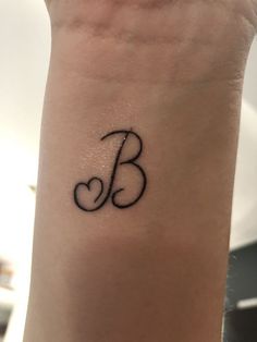 a woman's arm with a small tattoo on it that reads b and heart