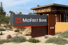 a sign for the mid - first bank is shown in front of some bushes and trees