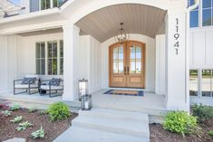 the front entrance to a home with steps leading up to it and two chairs on the porch