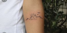 a person with a tattoo on their arm that has mountains and birds in the sky