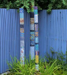 a tall blue pole sitting in the middle of a garden next to a blue fence