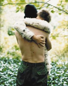 two people hugging each other in the woods