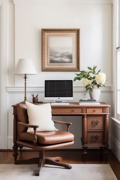 a desk with a chair and a computer on it in front of a framed photo