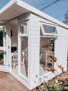 a small white shed sitting on top of a brick patio