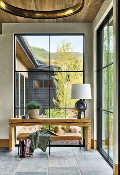 the inside of a house with large windows and a wooden bench in front of it