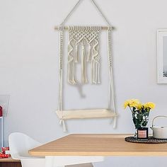 a dining room table and chairs with macrame hanging from the wall above it