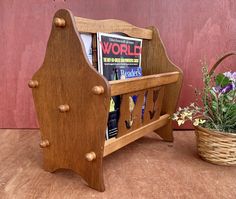 a wooden bench with magazines on it next to a potted plant