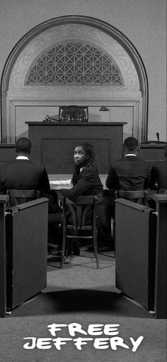 a black and white photo of people sitting at desks in front of a speaker