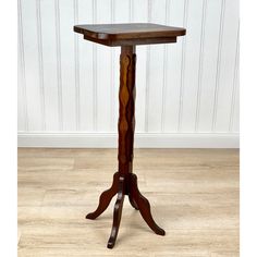 a small wooden table with an ornate design on the top and legs, sitting on a hard wood floor