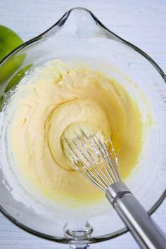 a glass bowl filled with batter next to an apple