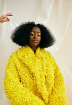 a woman with bright yellow eyeshades and an afro is posing for the camera