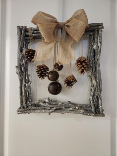 a wooden frame with pine cones and bells hanging from it's side, decorated with burlap