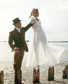 a man and woman standing on top of a wooden post