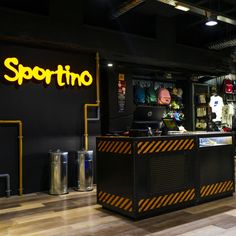 a man sitting at a desk in front of a neon sign that says sportino