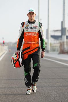 a man in an orange and black outfit is walking down the street with his helmet on