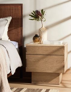 a bedroom with a bed, nightstand and flower pot on the night stand in front of it