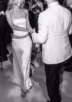 black and white photo of two people in formal wear dancing at an event with other people