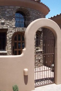 a gated entrance to a house with stone walls and arched doorways on the side