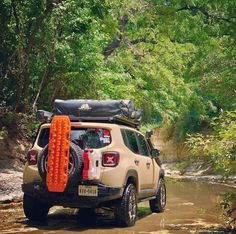 an suv is parked in the middle of a muddy road with orange decorations on it