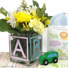 a vase filled with yellow flowers next to a green toy car