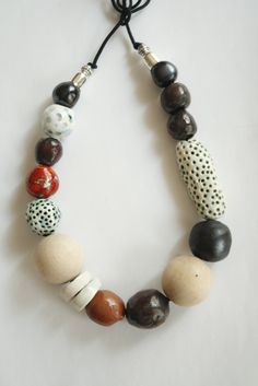 a multi - colored beaded necklace with black, white and red beads hanging from a cord