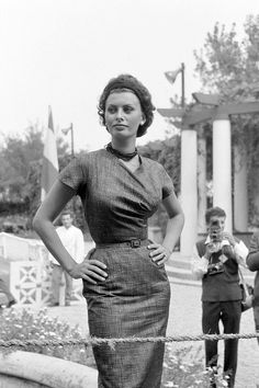 a woman standing in front of a fence with her hands on her hips and two men behind her