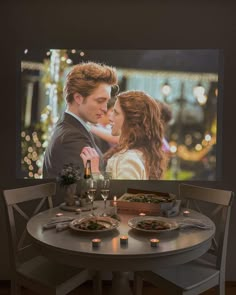 a table with food and candles on it in front of a screen showing the twilight movie