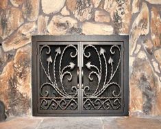 an iron gate is shown in front of a stone fireplace mantel with decorative designs on it