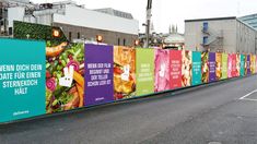 a long line of colorful billboards on the side of a road in front of buildings