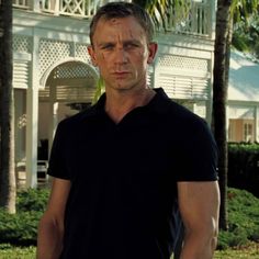 a man standing in front of a white house with trees and bushes around his neck