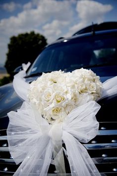 a bouquet of white roses sitting on the hood of a car