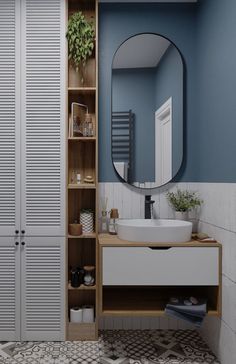 a bathroom with blue walls, white cabinets and a round mirror on the wall above the sink