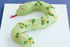 a cake shaped like a snake with green and yellow sprinkles on it