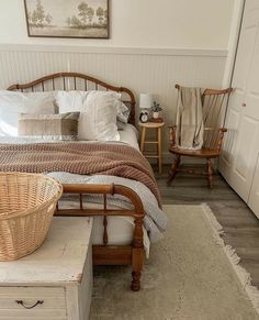 a bed sitting in a bedroom next to two wooden chairs and a table with a basket on it