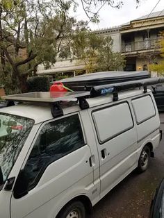 a white van parked in front of an apartment building with surfboards on top of the roof