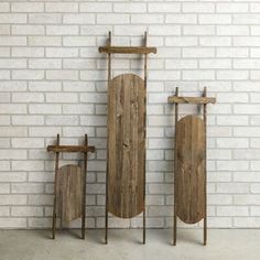 three pieces of wood sitting next to each other on top of a white brick wall