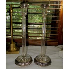 two glass candlesticks sitting on top of a table next to a lamp shade