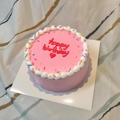 a birthday cake with pink frosting and sprinkles that says happy birthday