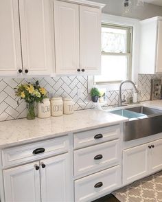 a kitchen with white cabinets, marble counter tops and stainless steel sink in the center