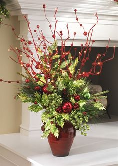 a potted plant with red berries and greenery in front of a fireplace mantel